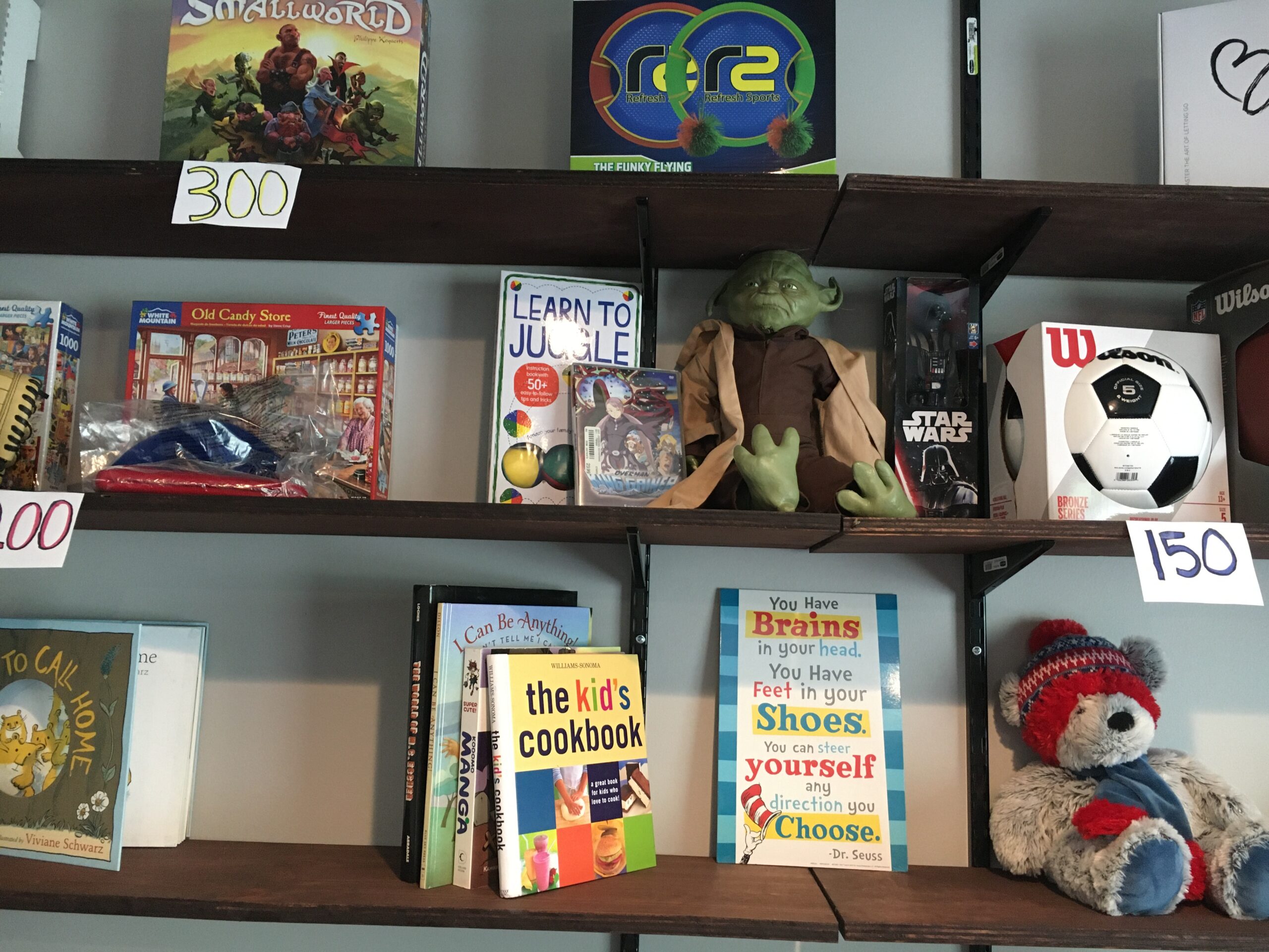 3 shelves filled with books, puzzles, hats and other childrens toys