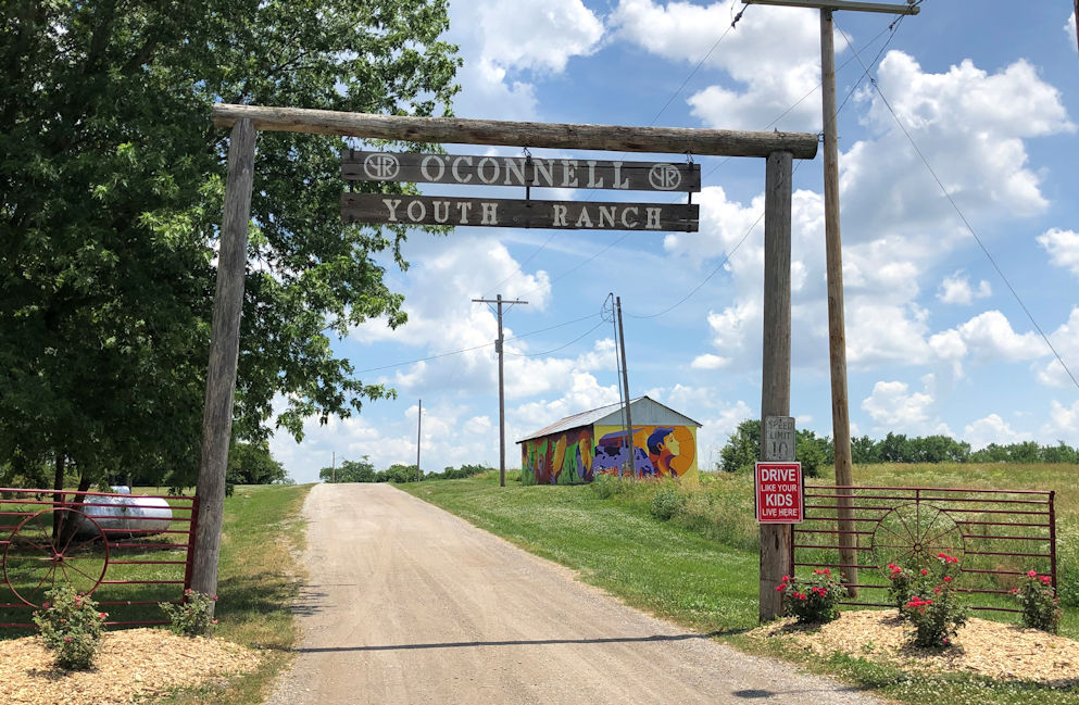 gravel road with a large wooden sign over it reading O'Connell Youth Ranch